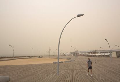 Un peatón camina por el puerto de Tel Aviv bajo un cielo brumoso.