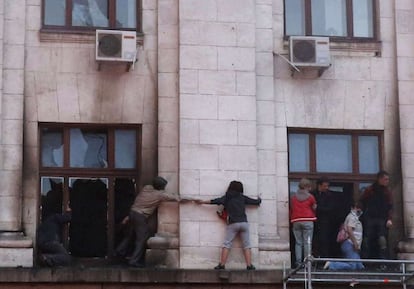 La gente trata de escapar del humo y el fuego caminando por las cornisas de las ventanas. 