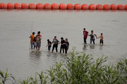 La instalación de esta barrera flotante, al igual que otras medidas del plan migratorio de Abbott, ha sido impugnada por diferentes colectivos. Sin embargo, el republicano ha asegurado que su Estado tiene el derecho de proteger sus fronteras, y que espera que el Gobierno federal lo apoye en esta labor. En la imagen, tres familias de migrantes cruzan el río Bravo junto a la barrera de boyas.