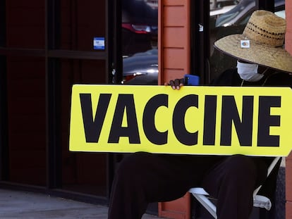 Un hombre sostiene un cartel indicador de un centro de vacunación, en Los Ángeles (California).