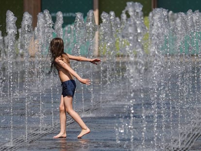 Un niño juega con chorros de agua en un día de calor en Moscú, Rusia. 