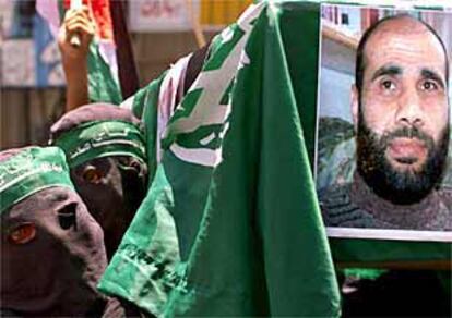 Dos militantes enmascarados de Hamás portan un retrato de Jamal Mansur, un dirigente de esa organización muerto en el ataque israelí.