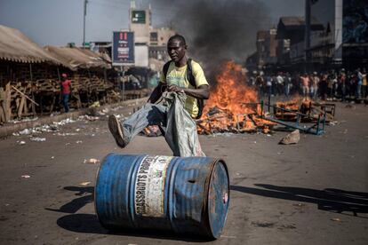 Un partidario de la oposición zimbabuense MDC empuja un barril frente a un incendio en Harare, el 1 de agosto de 2018.