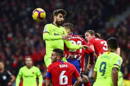 El defensa del FC Barcelona Gerard Piqué cabecea el balón ante jugadores del Atlético de Madrid.