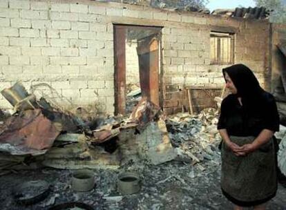 Una anciana observa las ruinas de su vivienda destruida por el fuego en la aldea de Platiana, cercana a Olimpia.