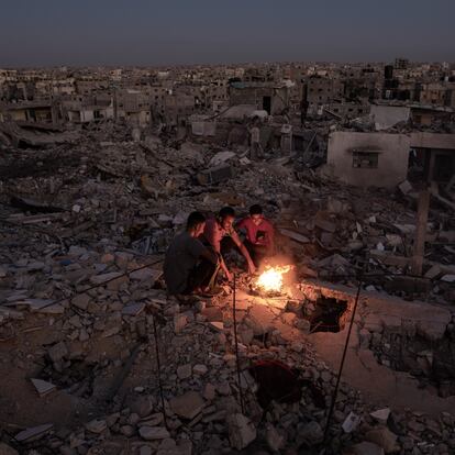 Gaza (-), 20/10/2024.- Palestinians sit next to a fire on the rubble of their destroyed home in Khan Yunis, southern Gaza Strip, 20 October 2024. More than 42,500 Palestinians and over 1,400 Israelis have been killed, according to the Palestinian Health Ministry and the Israel Defense Forces (IDF), since Hamas militants launched an attack against Israel from the Gaza Strip on 07 October 2023, and the Israeli operations in Gaza and the West Bank that followed it. EFE/EPA/HAITHAM IMAD