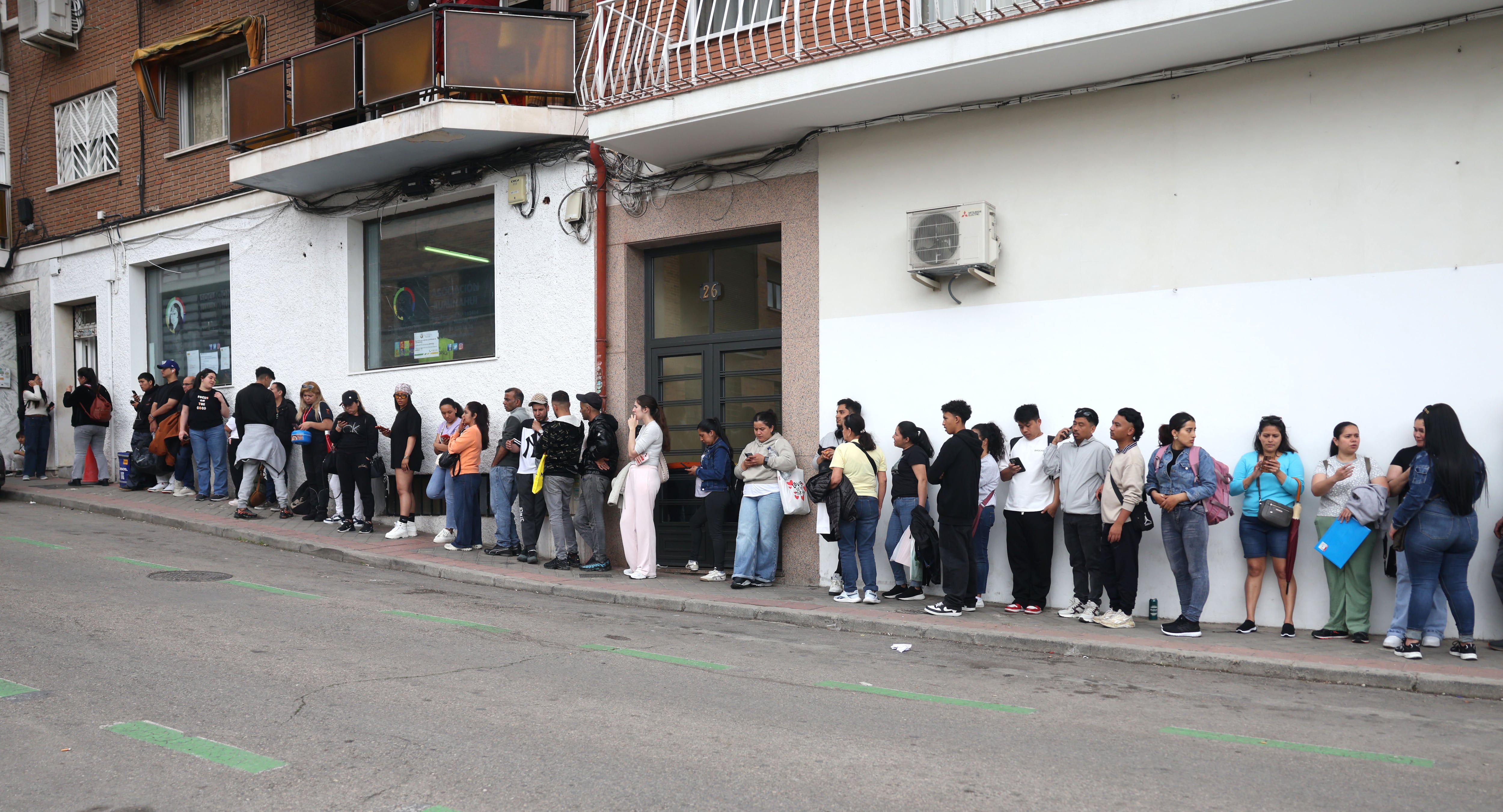 Decenas de inmigrantes esperan para regularizar sus papeles frente a la Asociación Rumiñahui de Madrid.