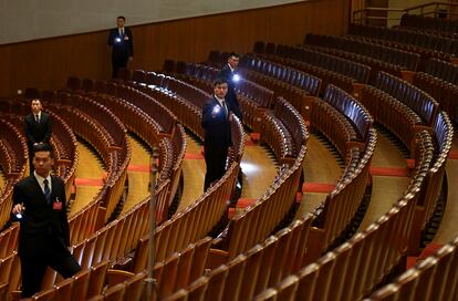 Personal de seguridad usan linternas para mirar entre los asientos tras terminar una sesión plenaria del Congreso Nacional del Pueblo en el interior del Gran Salón del Pueblo en Pekín (China), el 9 de marzo de 2018.