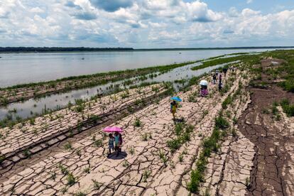 Un grupo habitantes caminan sobre una parte del río Amazonas que muestra signos de sequía en Santa Sofía, en las afueras de Leticia, Colombia, el 20 de octubre de 2024. 