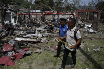 Dos hombres caminan junto a una vivienda destruida por un ataque con carro bomba, en Timba (Colombia), este miércoles.