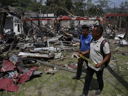 Dos hombres caminan junto a una vivienda destruida por un ataque con carro bomba, en Timba (Colombia), este miércoles.