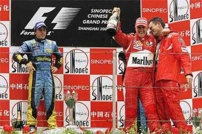 Alonso, en el podio junto a Schumacher, que se abraza a Chris Dyer, ingeniero de Ferrari.