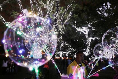 Un hombre vende globos con iluminaciones navideñas entre árboles decorados en el parque Ibirapuera en Sao Paulo (Brasil), el 3 de diciembre de 2018.