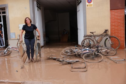 A woman carries out folding chairs caked in mud after torrential rains caused flooding in La Alcudia, Valencia region, Spain, October 30, 2024. 