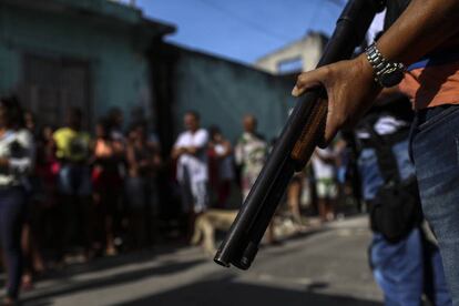 Moradores de Vitória se aglomeram enquanto a polícia civil retira os cadáveres de duas mulheres assassinadas.