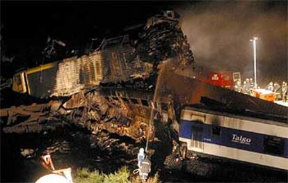 La máquina del mercancias aparece montada sobre los primeros vagones del Talgo, mientras los bomberos intentan enfriar los restos calcinados.