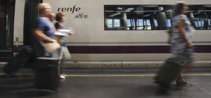 Varios viajeros esta ma&ntilde;ana en la estaci&oacute;n de Atocha delante de un AVE.