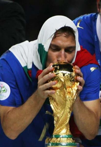 El jugador de la selección italiana Francesco Totti, ataviado con la bandera de su país sobre su cabeza, besa la copa de campeona del mundo 2006.