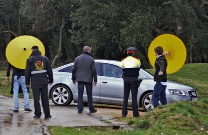 Agentes intentan tapar con paraguas el coche de Mas a su llegada.