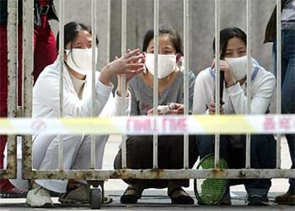 Tres mujeres, tras la verja del hospital del Pueblo, aislado del exterior desde el jueves.