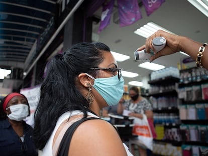 Uma vendedora mede a temperatura de uma cliente antes de ela entrar em uma loja de São Paulo.