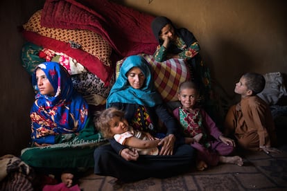 Zheela, en el centro de la imagen, abandonó su hogar hace cinco años debido a la sequía, y se instaló en el mismo campo de refugiados. Tiene 35 años y siete hijos: cuatro niñas y tres niños de entre uno y 15 años. El año pasado, su marido murió en un accidente de coche en Irán, adonde había ido a buscar trabajo. Zheela tuvo que pedir dinero prestado para sobrevivir, pero como sus deudas aumentaban, se vio obligada a vender a su hija Malalai (de pie), de nueve años, por 300.000 afganis, unos 3.875 euros. El comprador insiste en que ahora tiene derecho a llevársela porque no hay ningún hombre en casa. Para las niñas, los matrimonios a tan corta edad son una pesadilla. En casa de sus nuevos suegros, se ven obligadas a realizar tareas domésticas y a menudo sufren abusos verbales, físicos y sexuales: esclavitud disfrazada de matrimonio. Zheela está luchando por la vía legal para quedarse con Malalai hasta que cumpla 18 años. Estos días, la madre hila lana para ganar algo de dinero. La comida de los niños consiste en pan, a veces té, si encuentran algo para quemar y calentar el agua. Muy rara vez, cuando los niños piden limosna a los vecinos, consiguen comer arroz. En la imagen, Zheela, con sus hijos de 13, dos, cinco, siete y nueve años. 