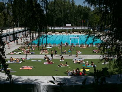 Vista de varias personas disfrutando de la piscina municipal de El Lago, en Casa de campo (Madrid) en julio de 2023.