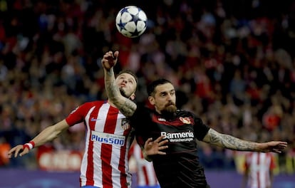 El centrocampista del Atlético de Madrid Saúl Ñíguez (i) salta por el balón con Roberto Hilbert, defensa del Bayer Leverkusen.