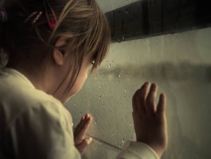 Una niña mira por la ventana.