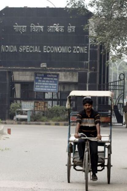 Un hombre pedalea frente a la zona especial de Noida, junto a Nueva Delhi (India).