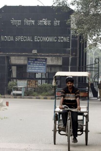 Un hombre pedalea frente a la zona especial de Noida, junto a Nueva Delhi (India). 