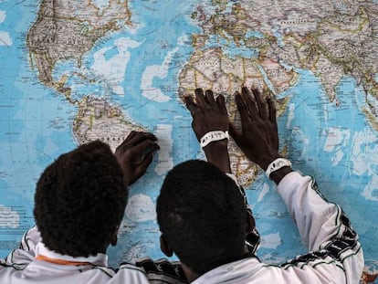 Dos menores de Gambia solicitantes de asilo en Italia, discuten sobre el viaje que han realizado en un mapa en el puerto de Pozzallo, Sicilia.