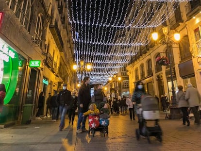 Varios viandantes, en la calle Alfonso I de Zaragoza, adornada con el alumbrado navideño.