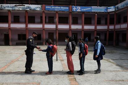 Un guardia de seguridad da desinfectantes de manos a los estudiantes cuando llegan a la escuela secundaria de Prabhat. Algunas escuelas han reabierto después de un cierre de seis meses debido a la pandemia del coronavirus covid-19 en el municipio de Chandagiri, en las afueras de Katmandú.