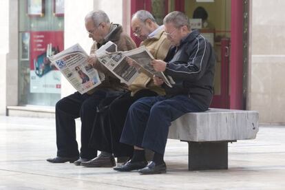 Un grupo de ancianos lee el periódico