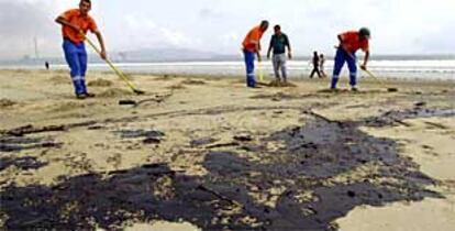 Unos empleados realizan labores de limpieza en la Playa de El Rinconcillo.