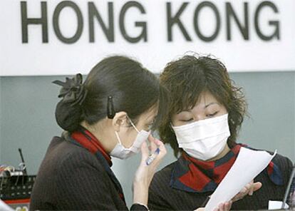 Dos azafatas de vuelo trabajan en Hong Kong usando máscarillas para protegerse de la neumonía asiática.