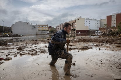 Un voluntarios intenta mover el lodo con una pala en un descampado de Paiporta el 22 de noviembre.