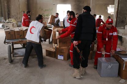 Un combatiente rebelde vigila los trabajos de la Media Luna Roja en el cruce de Garage al-Hajz, en el barrio de Bustan al-Qasr.