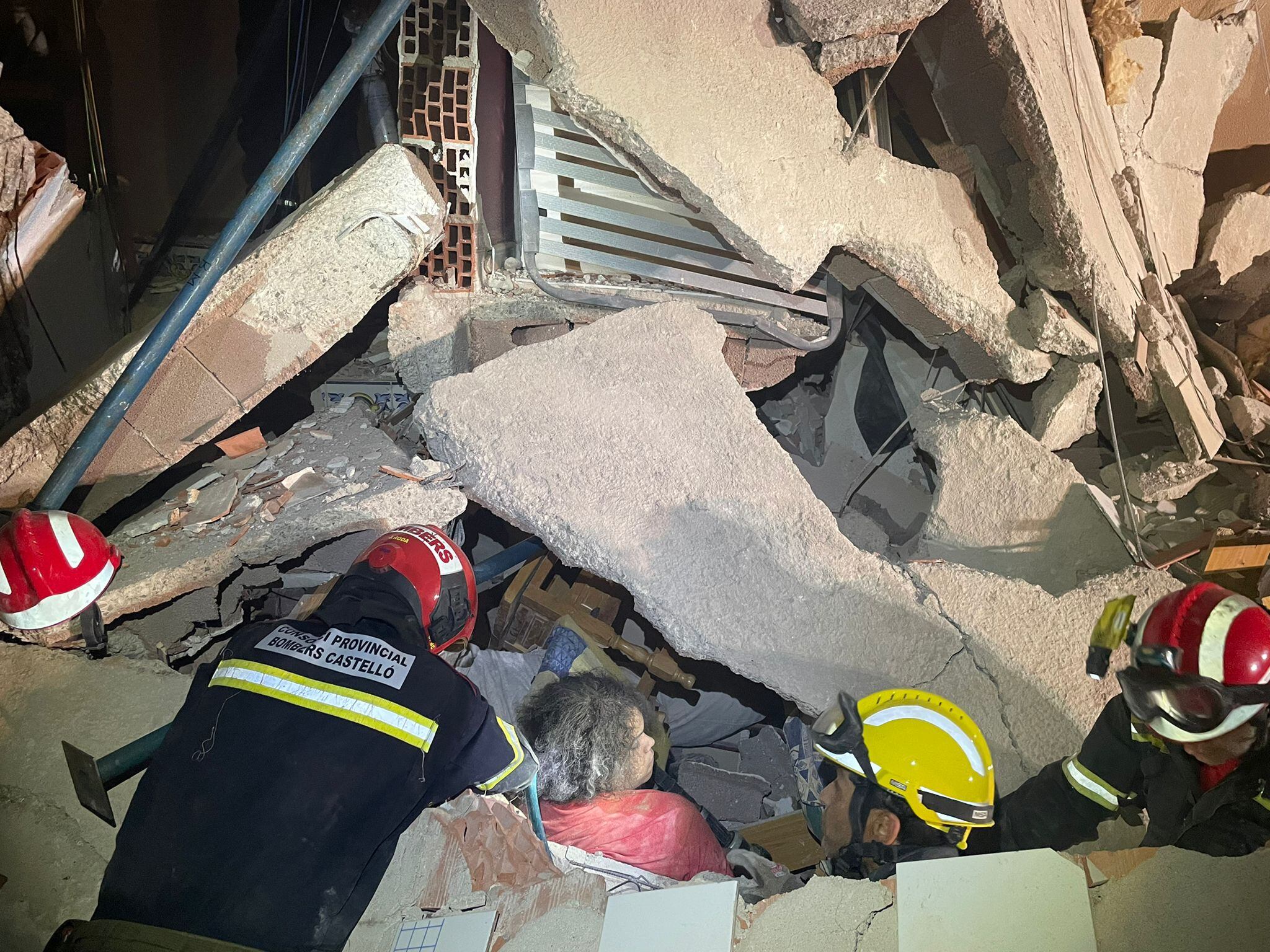 Los bomberos rescatan con vida a una de las tres personas sepultadas.