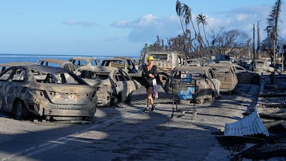 A woman walks through wildfire wreckage Friday, Aug. 11, 2023, in Lahaina, Hawaii. 