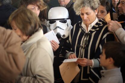 Un niño con una careta de un personaje de la saga de 'Star Wars' en un colegio electoral de Aravaca.
