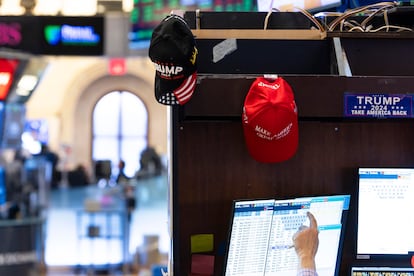 Varias gorras de apoyo a Donald Trump cuelgan de las pantallas de unos 'traders' de Wall Street.