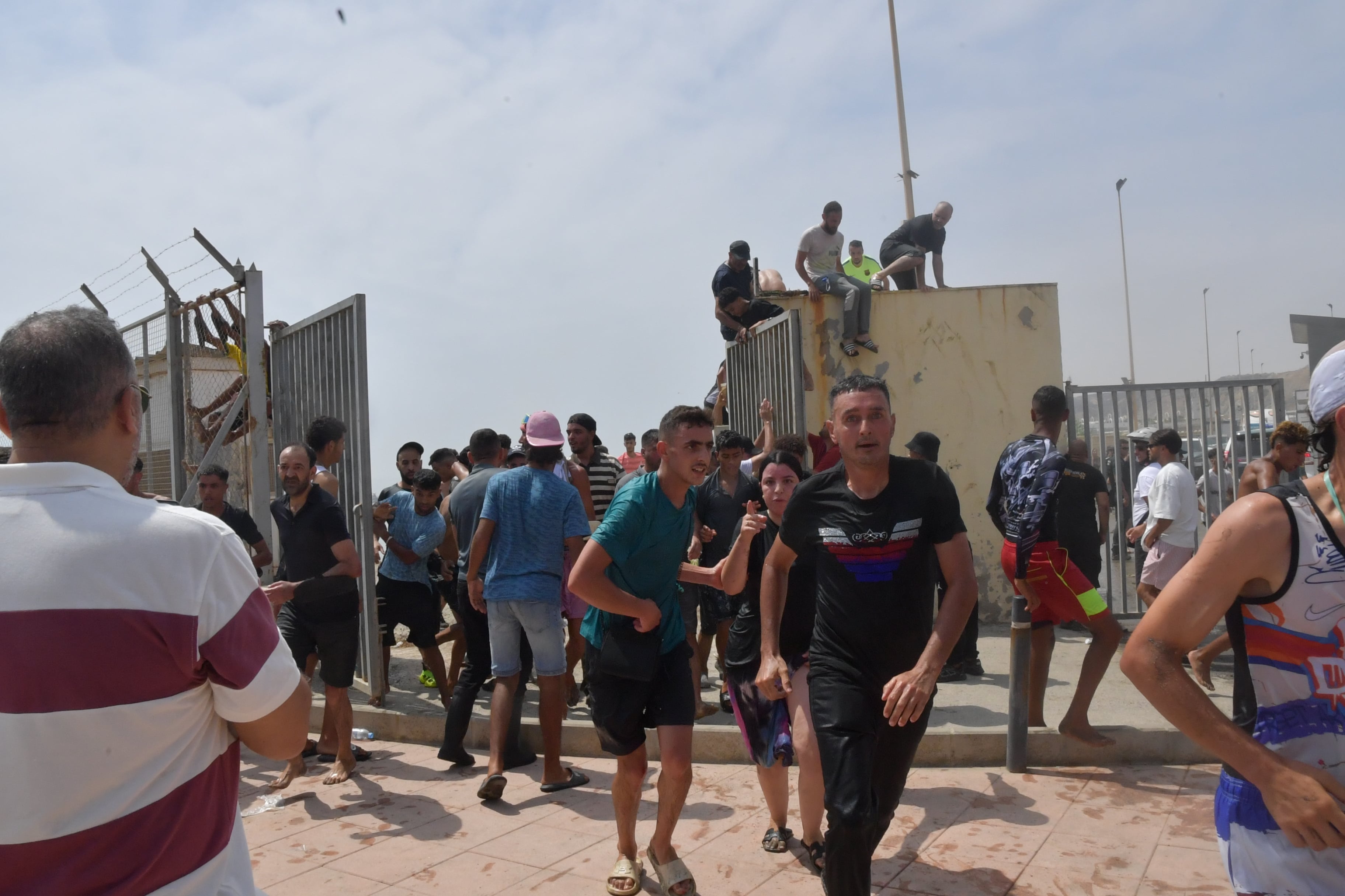 Migrantes marroquíes saltan una puerta lateral de la frontera de Ceuta, el 30 de julio.