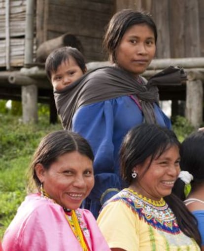 Grupo de mulheres embera ao lado de uma de suas casas