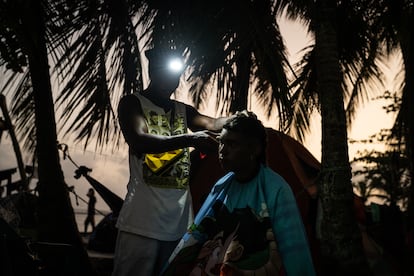 Cali rapper Turbo cuts another migrant's hair as night falls.