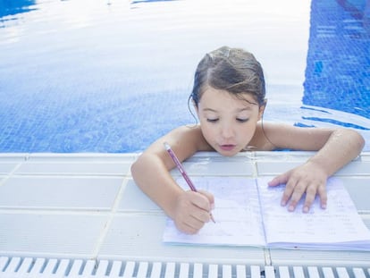 Una niña haciendo deberes en la piscina.