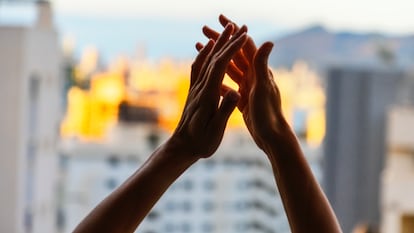 Las manos de una mujer aplauden desde un balcón en apoyo a los sanitarios durante la pandemia.