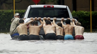 Un grupo de personas empuja un coche atascado en el agua, en Houston, el 27 de agosto de 2017.