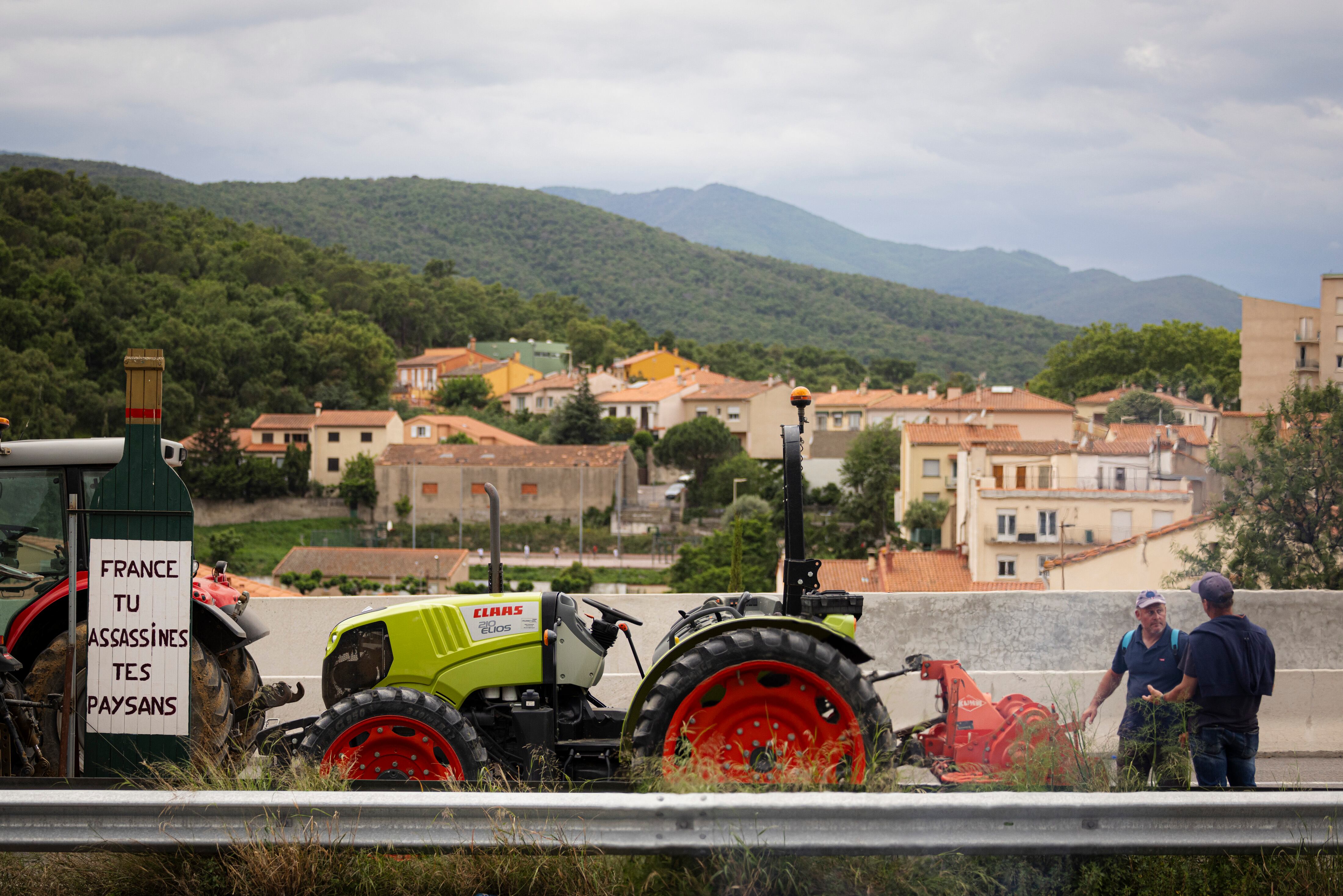 Agricultores catalanes y franceses bloquean la carretera que conduce a Francia con tractores, a la altura del Perthus, este lunes.  